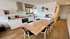 a kitchen and dining room with a wooden table and chairs at Superbe appartement avec 2 chambres avec vue imprenable sur les Alpes in Crans-Montana