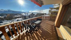 a deck with a table and chairs on a balcony at Superbe appartement avec 2 chambres avec vue imprenable sur les Alpes in Crans-Montana