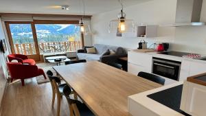 a kitchen and living room with a table and a couch at Superbe appartement avec 2 chambres avec vue imprenable sur les Alpes in Crans-Montana