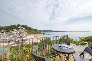 Un balcón con mesa y sillas y una playa. en 4 Bed in Looe oc-l30051, en Looe