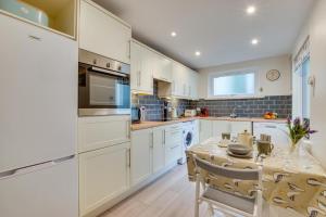 a kitchen with white cabinets and a table with chairs at 2 Bed in Looe oc-l10082 in Looe