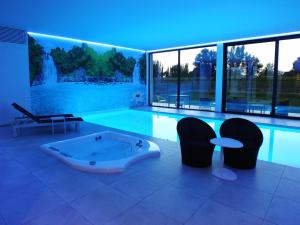 a large swimming pool with a tub and chairs at Vita Roka met extra Luxe Privé Wellness in Ursel