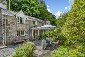 een oud stenen huisje met een parasol en een tafel bij 2 Bed in Looe oc-l30015 in Lansallos