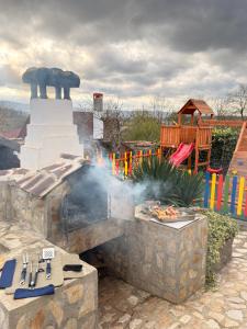een barbecue waar rook uit komt naast een speeltuin bij Вила Лонгоз 