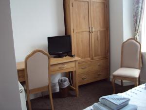 a bedroom with a desk with a television and a cabinet at Mountbatten Hotel in Plymouth
