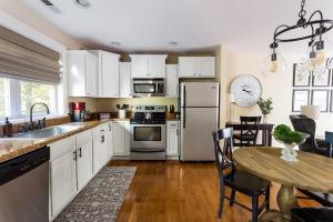 a kitchen with white cabinets and a wooden table at The Maple Cottage in Asheville