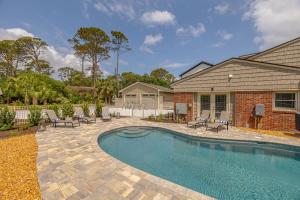 a swimming pool with chairs and a house at 8 Stewart Lane in Jekyll Island