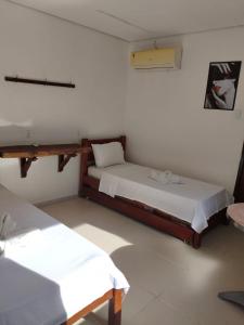 una camera con due letti e una croce sul muro di Quarto Duplo com Ar e Banheiro Privativo a poucos metros do mar a Porto De Galinhas