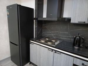 eine Küche mit einem schwarzen Kühlschrank und einem Herd in der Unterkunft Apartment NEW in Taschkent + 18 Fotos
