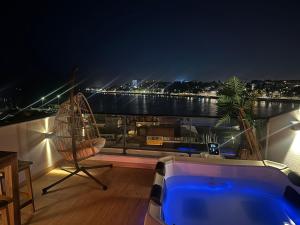 a balcony with a hot tub and a view of the water at Trihouse Douro and Sea View - jacuzzi only in Room 4 - Jacuzzi apenas no quarto 4 in Vila Nova de Gaia