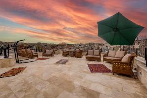 un patio con sedie e un grande ombrellone verde di Erbelya Cappadocia House a Göreme