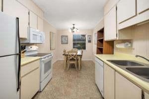 a kitchen with white cabinets and a table with a chair at 1055 College in Saint Simons Island +16 photos