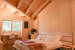 a bedroom with a bed and a desk and a window at La Presentosa guest house in Villalago
