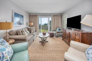 a living room with a couch and a tv at Beach Club #211 in East End