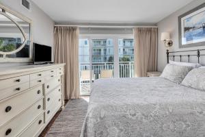 a bedroom with a bed and a television and a balcony at Beach Club #211 in East End +22 photos
