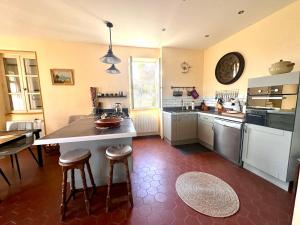 een keuken met een groot eiland met krukken erin bij Villa Le Chant du Tilleul in Le Poët-Laval
