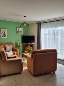 een woonkamer met 2 stoelen en een flatscreen-tv bij Chez Carisa in Puilboreau