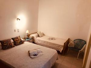 een hotelkamer met twee bedden en een stoel bij Che in Necochea +15 foto's