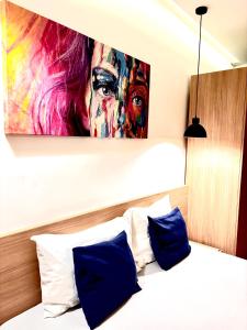 ein Schlafzimmer mit einem Gemälde über einem Bett mit blauen Kissen in der Unterkunft City Heart Apartments Belgrade Free Wi-Fi Self Check-in Central Location in Belgrad