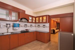 eine Küche mit Holzschränken, einer Spüle und einem Kühlschrank in der Unterkunft Vensa corporate Inn in Bhubaneshwar