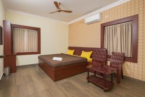 ein Schlafzimmer mit einem Bett, einer Couch und einem Stuhl in der Unterkunft Vensa corporate Inn in Bhubaneshwar