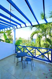 a balcony with a table and chairs and palm trees at Brisa de Alma Guesthouse in Bayahibe