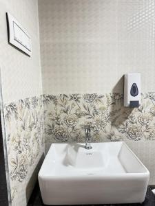 Baño con lavabo blanco y papel pintado con motivos florales en Royal Casa Resort Diveagar, en Borlai Panchaitan