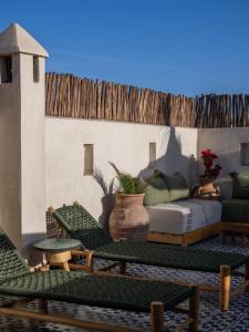 a patio with green chairs and a couch at Riad le myrath in Essaouira
