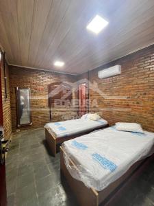 una camera con due letti e un muro di mattoni di Chácara passárgada a Gravatá