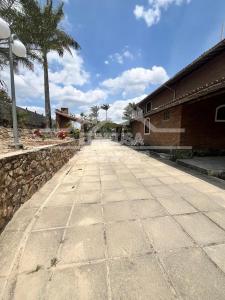 an empty street with a stone wall and palm trees at Chácara passárgada in Gravatá +5 photos