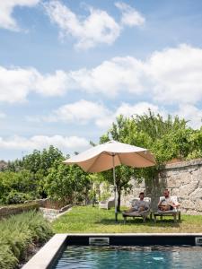two people sitting under an umbrella next to a pool at Oakstone Hills in Nelas