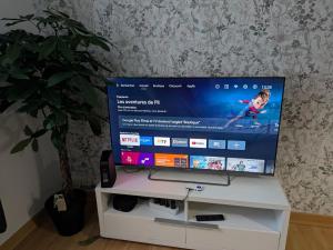 einen Flachbild-TV auf einem weißen Schrank in der Unterkunft CAPUCiNE-Appartement Retro-chic & idéalement situé in Vitré