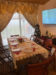 een eettafel met een kerstboom voor een raam bij Cabana Nys Escape in Bălceşti +33 foto's