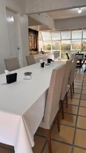 Adegas Bar e Hotel في ساو غابرييل: طاولة بيضاء كبيرة وكراسي في غرفة