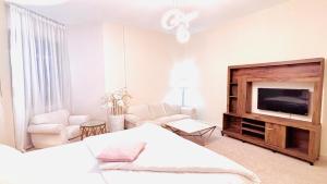 a white bedroom with a bed and a tv at Canel View Holiday Home with Parking in Ajman 