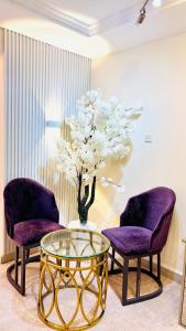 deux chaises violettes et une table en verre avec un vase dans l'établissement Sea View Holiday Home with Parking, à Ajman