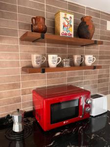 un forno a microonde rosso seduto su un bancone in cucina di Domus Mangana a Cuenca