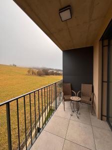 a balcony with two chairs and a view of a field at Apartmán nad Dolným Kubínom in Dolný Kubín