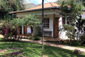 una piccola casa bianca con una panchina nel cortile di Pousada da Serrinha a Mariana