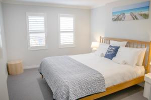 a bedroom with a bed with white walls and windows at Balneaire 13 in Albany