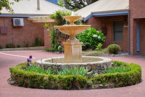 a fountain in the middle of a courtyard with flowers at Balneaire 13 in Albany
