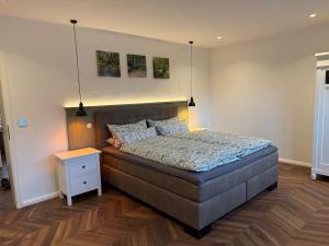 a bedroom with a large bed and a night stand at Fewo Voßbarg ünnen in Rastede +6 photos