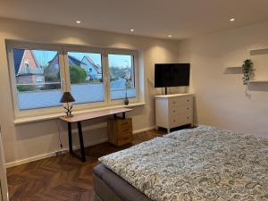 a bedroom with a bed and a desk and a television at Fewo Voßbarg ünnen in Rastede