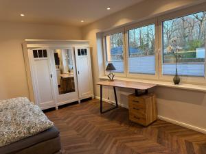 a bedroom with a desk and windows and a bed at Fewo Voßbarg ünnen in Rastede