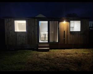 een klein huisje met een deur en ramen 's nachts bij Tinny House in Offemont