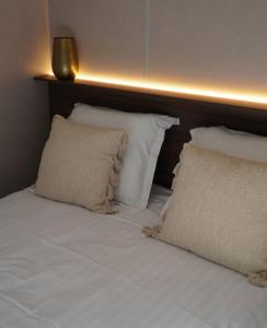 een bed met witte kussens en een licht erboven bij Tinny House in Offemont