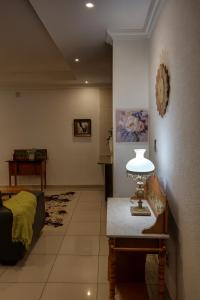 a living room with a bed and a table with a lamp at Agapantha Cottage in Lobamba