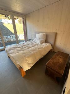 a bed in a room with a large window at Silenen Chalet I Andermatt I Ski I Berg I Familie in Silenen +15 photos