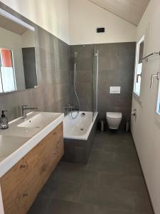 ein Badezimmer mit zwei Waschbecken und einer Badewanne und einer Toilette in der Unterkunft Silenen Chalet I Andermatt I Ski I Berg I Familie in Silenen + 15 Fotos