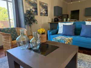 a living room with a blue couch and two glass vases on a table at Lilibeth guesthouse in Parys